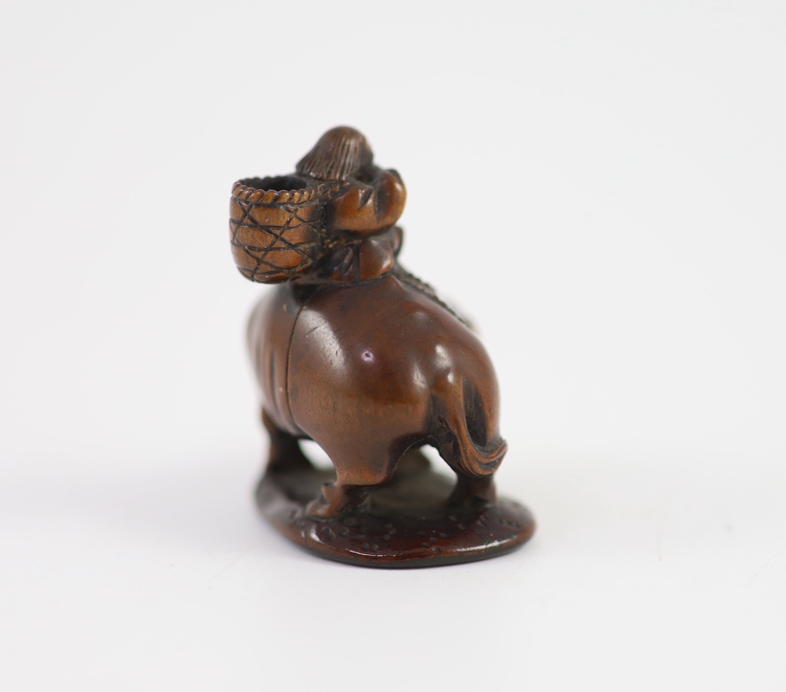 A Japanese boxwood netsuke of Semimaru playing the flute and riding upon an ox, School of Tomotada, early 19th century, 4cm high